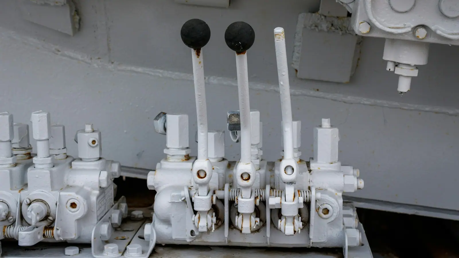 A bank of hydraulic directional control valves with black lever knobs, a typical proprietary part.