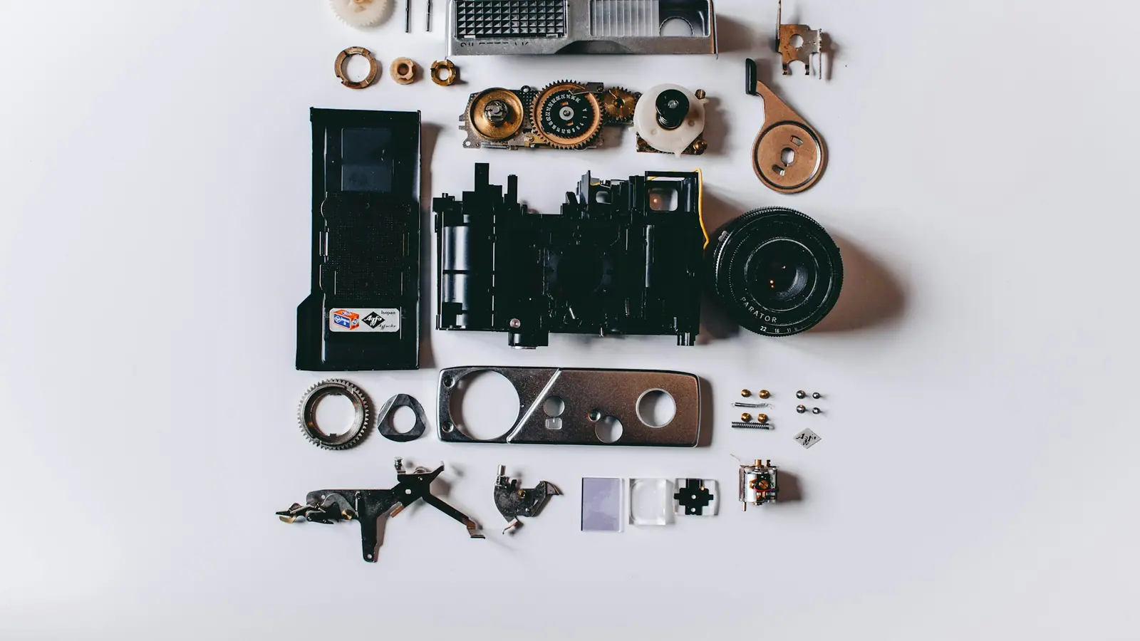 The parts of a disassembled camera laid out neatly on a white surface.