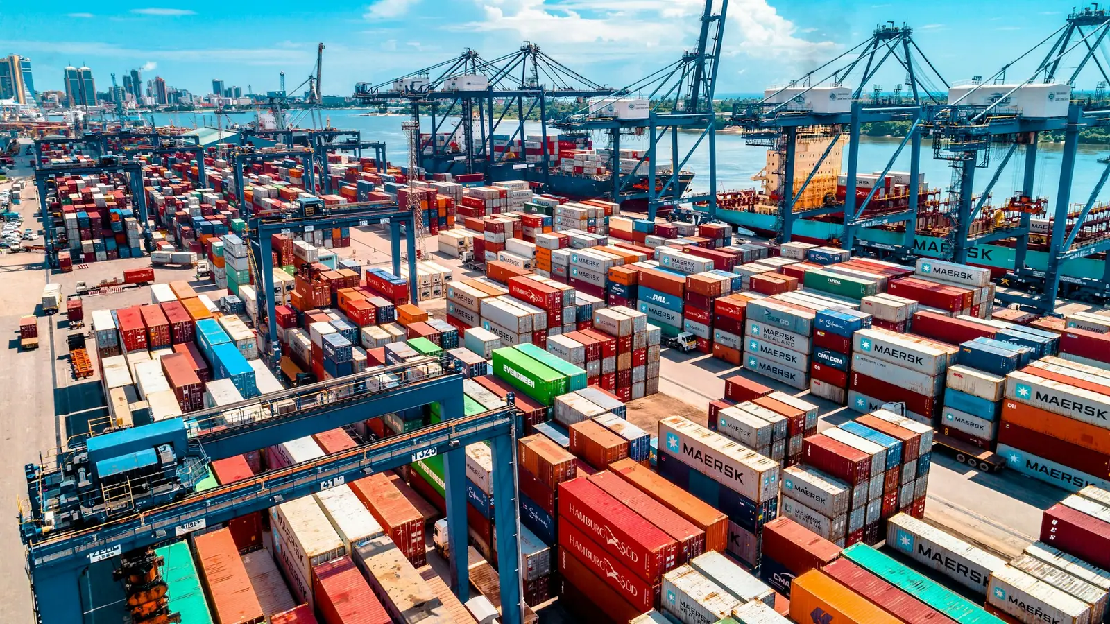 An aerial view of a container port, with cranes over stacked shipping containers.