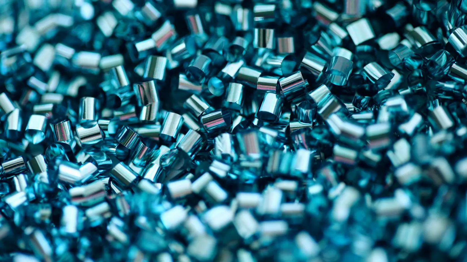 A close-up of blue translucent plastic granules used for injection moulding.